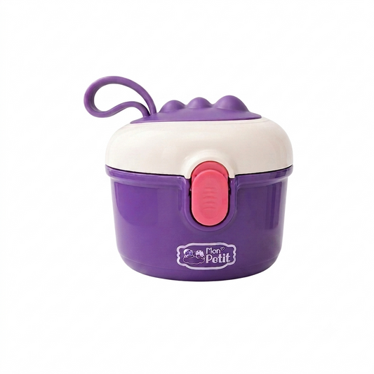 Caixa doseadora de leite em pó para bebé da marca Mon Petit, em tons de roxo e branco com fecho rosa, pousada num suporte circular sobre um fundo branco.