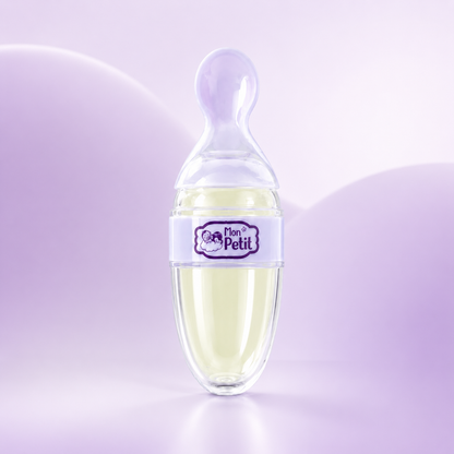 Colher dosadora infantil Mon Petit com reservatório preenchido por uma papa clara, colocada na vertical num cenário minimalista com fundo em tons de roxo e lilás pastel.