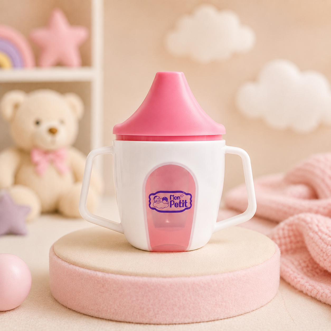 Copo de aprendizagem Mon Petit colocado num pódio cilíndrico rosa pastel no interior de um quarto infantil decorado com elementos decorativos suaves.