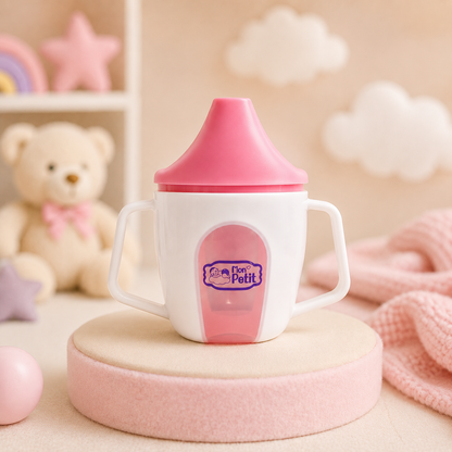 Copo de aprendizagem Mon Petit colocado num pódio cilíndrico rosa pastel no interior de um quarto infantil decorado com elementos decorativos suaves.