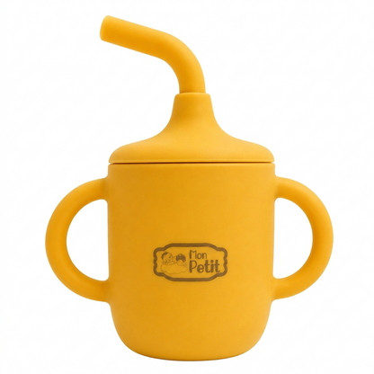 Copo de aprendizagem infantil totalmente feito de silicone cor de mostarda, com palhinha maleável integrada, duas alças laterais arredondadas e logótipo Mon Petit gravado ao centro.