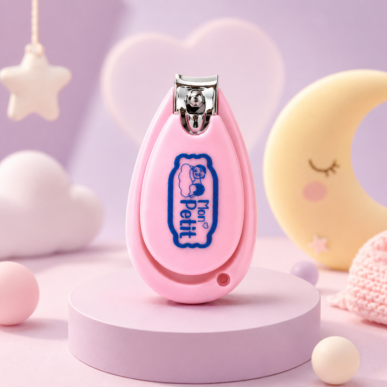 Cortador de unhas rosa para bebé em cima de um suporte, com decorações infantis de lua e estrela ao fundo.