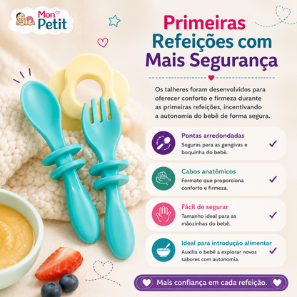 Garfo e colher de aprendizagem para bebé com cabos anatómicos azuis pousados ao lado de uma taça com papa de fruta e morangos frescos.