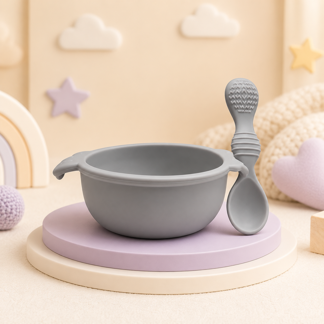Conjunto de tigela e colher para bebé em silicone cinzento num cenário decorativo infantil.
