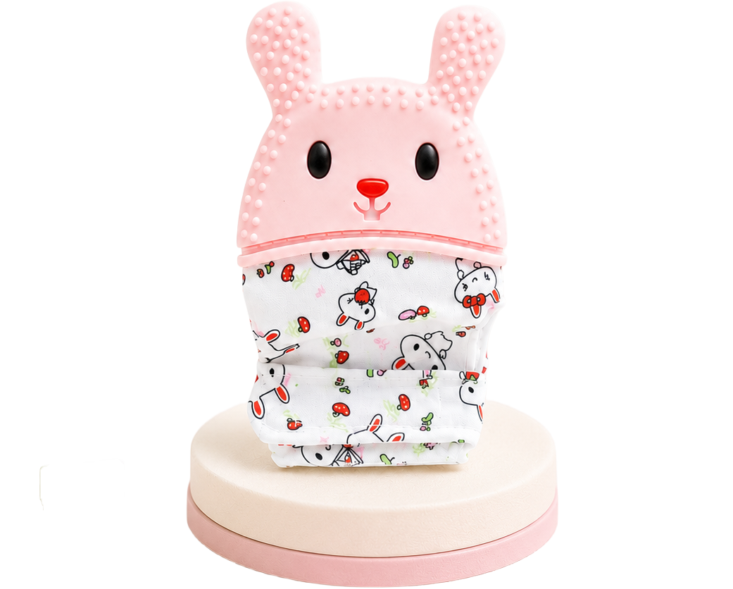 Luva mordedora infantil em formato de coelho rosa com relevos texturizados e base de tecido estampado com pequenos coelhinhos, isolada num suporte circular.