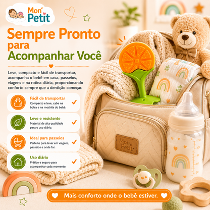 Mordedor de laranja espreitando de dentro de uma mochila de maternidade Mon Petit com uma manta, biberão e acessórios de bebé em redor.
