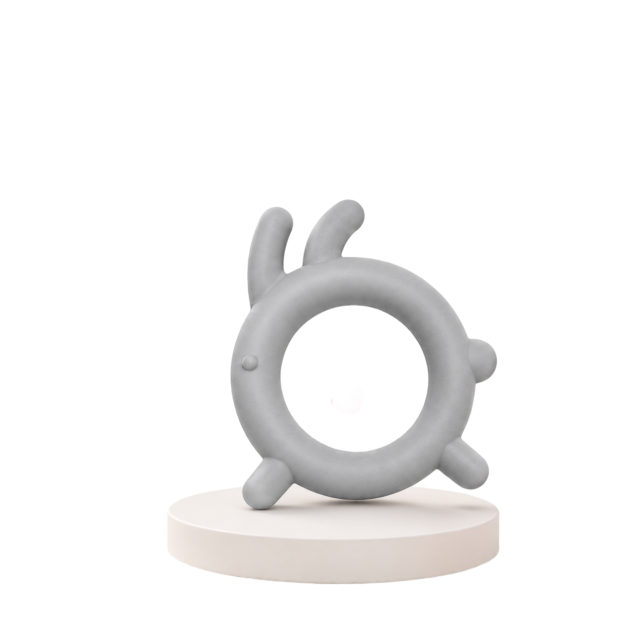 Mordedor sensorial para bebé em silicone macio cinzento com design circular e saliências ergonómicas, posicionado sobre um suporte redondo branco.