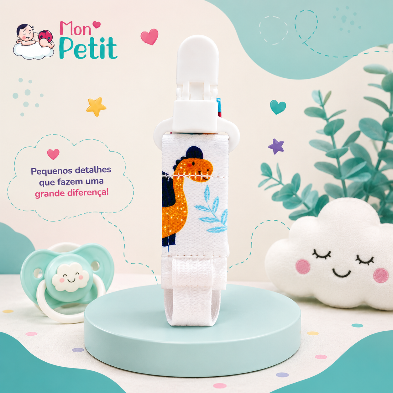 Prendedor de chupeta Mon Petit com estampa de dinossauro sobre um pódio azul-celeste, ao lado de uma chupeta verde e almofada em formato de nuvem com rosto sorridente.