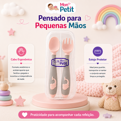 Apresentação dos talheres de bebé focada no design para pequenas mãos, evidenciando o cabo anatómico cinzento com relevo de baleia que facilita a preensão e incentiva a autonomia.